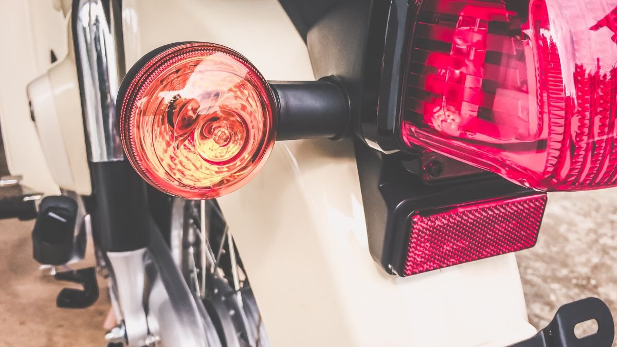 Nahaufnahme eines Blinkrelais mit orangefarbenem Blinker und rotem Rücklicht.