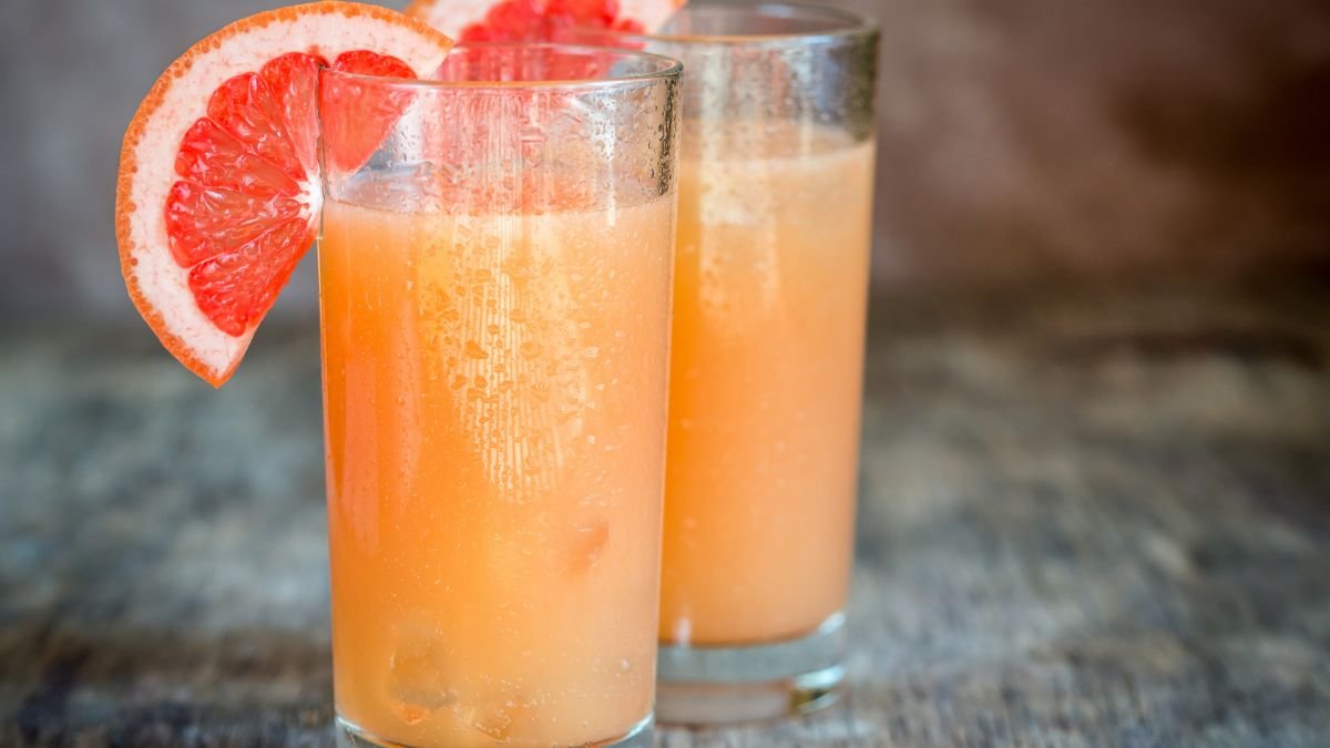 Zwei Gläser mit frisch gepresstem Grapefruitsaft, dekoriert mit Grapefruit-Scheiben.