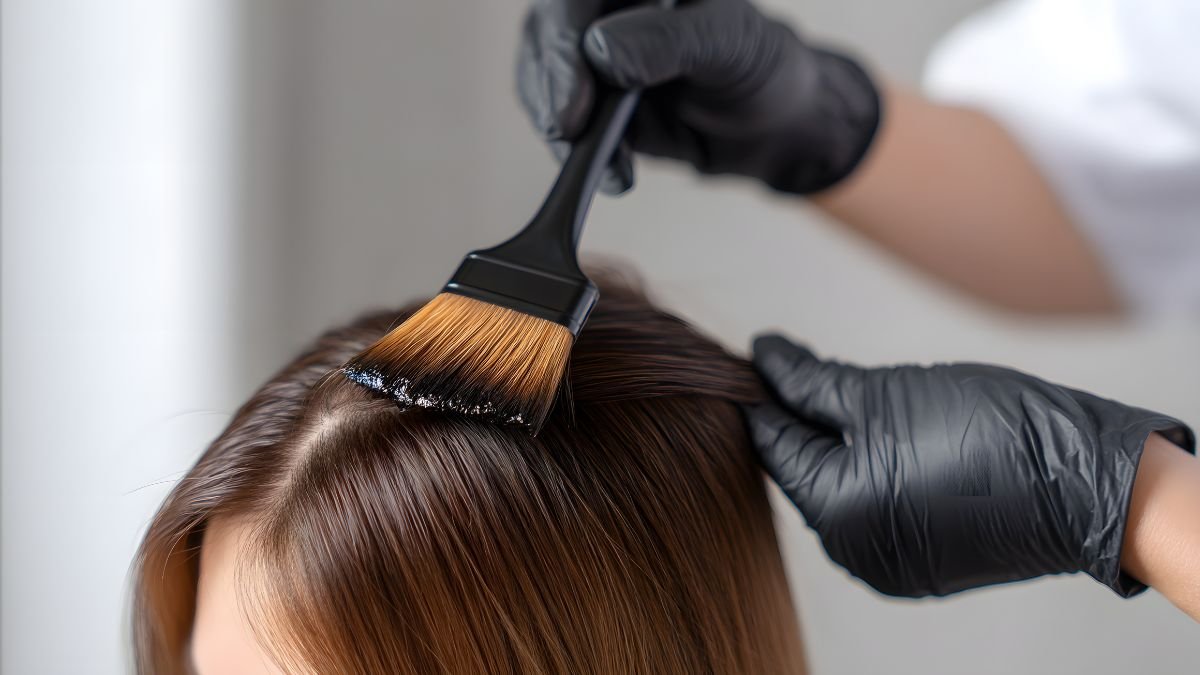 Eine Person färbt Haare mit einem Pinsel, während sie schwarze Handschuhe trägt.