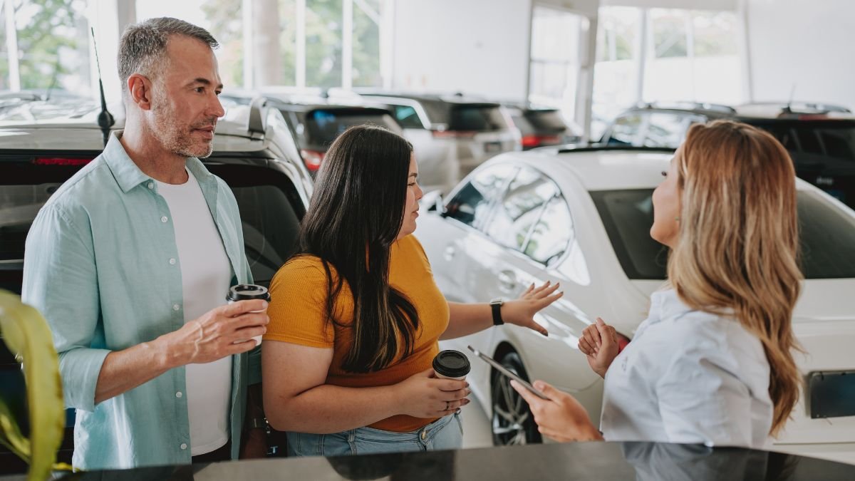 Ein Paar diskutiert mit einer Verkäuferin über Hybridautos in einem Autohaus.