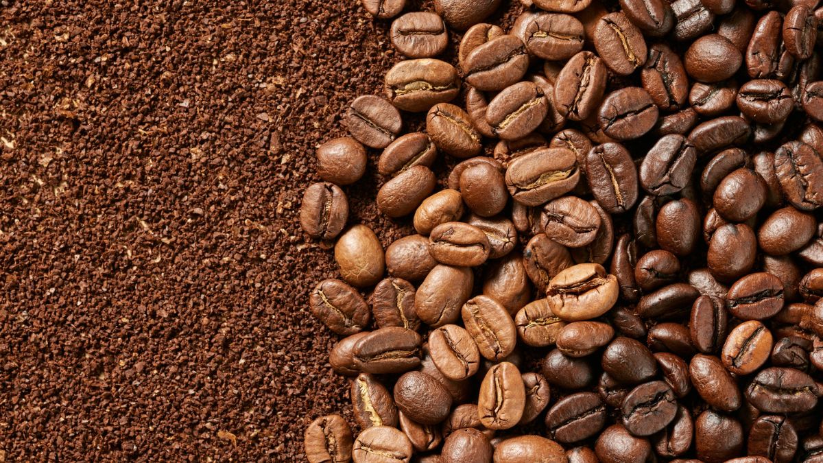 Eine Mischung aus gemahlenem Kaffee und ganzen Kaffeebohnen auf einem Holzuntergrund.