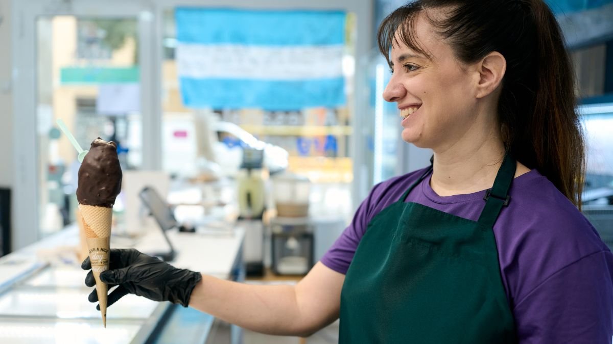 Eine Frau hält ein Schokoladeneis in einer Waffel in der Hand.