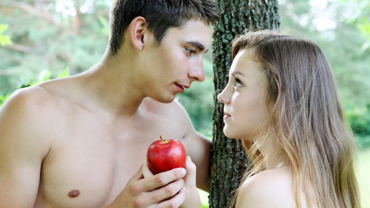 Ein junger Mann hält einen roten Apfel und schaut einer Frau in die Augen.