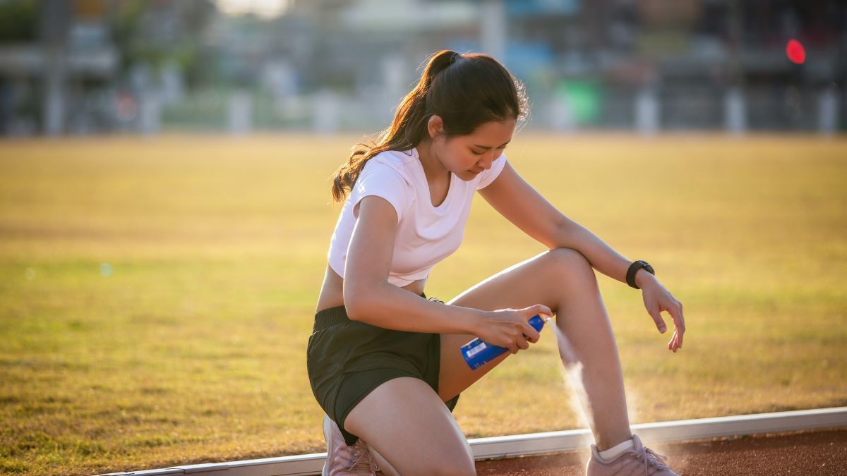 Eine Sportlerin sprüht Kältespray auf ihr verletztes Bein während des Trainings.