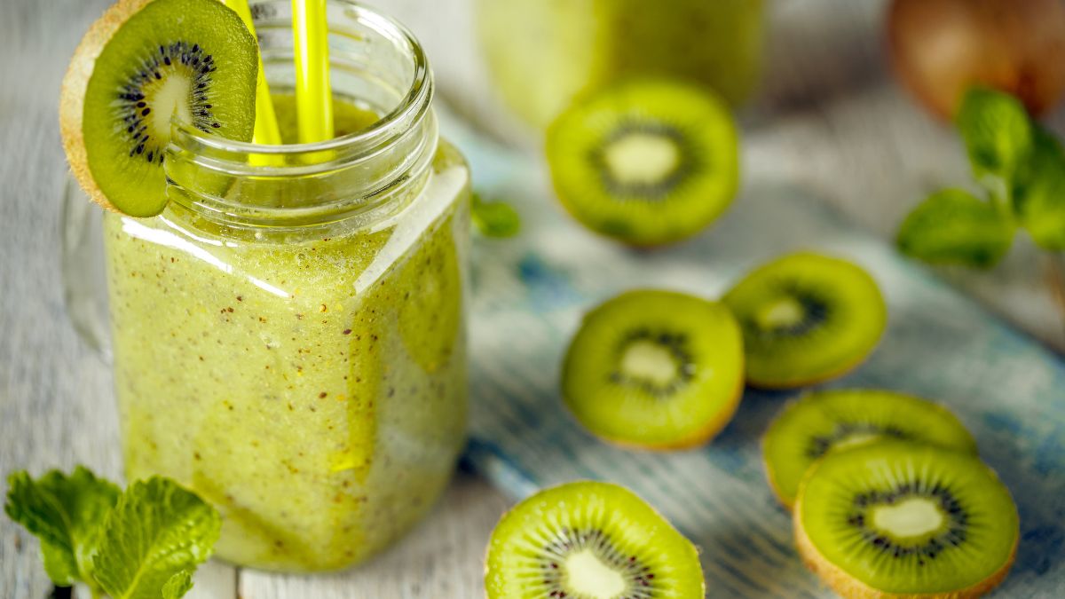Ein erfrischender Kiwi-Smoothie in einem Glas mit Kiwi-Scheiben und Minze.
