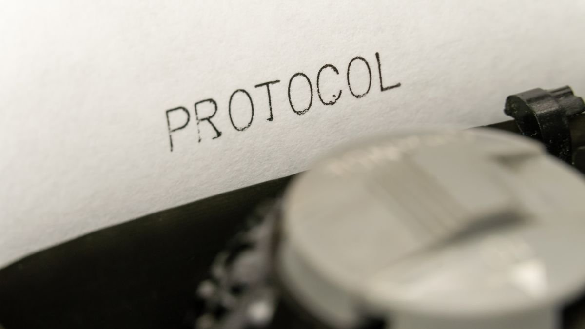 Nahaufnahme eines Papiers mit dem Wort 'PROTOCOL' und einer Schreibmaschine.