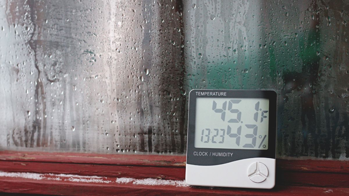 Ein Thermometer zeigt 45,1°F und 23,43% Luftfeuchtigkeit an, während Wassertröpfchen an einem Fenster hängen.