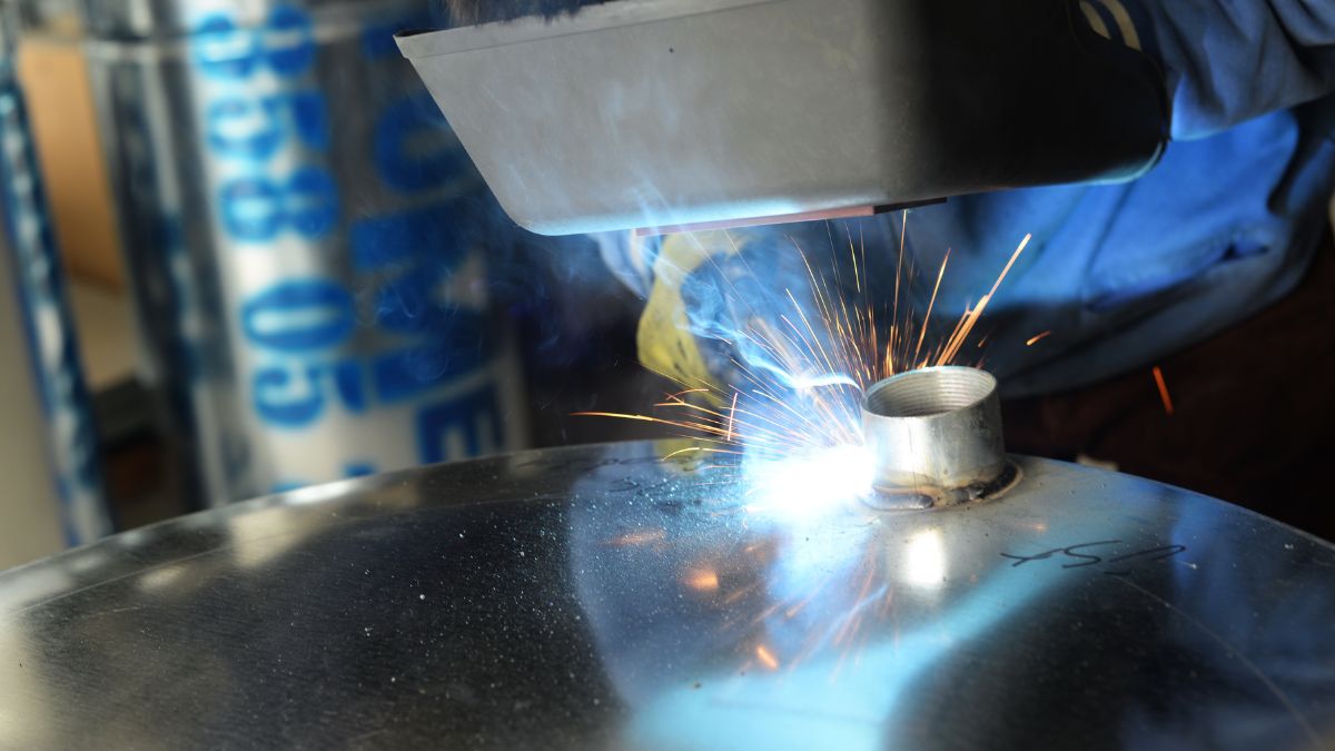 Ein Schweißer nutzt MIG-Technik, um Metallteile zu verbinden, Funken sprühen.