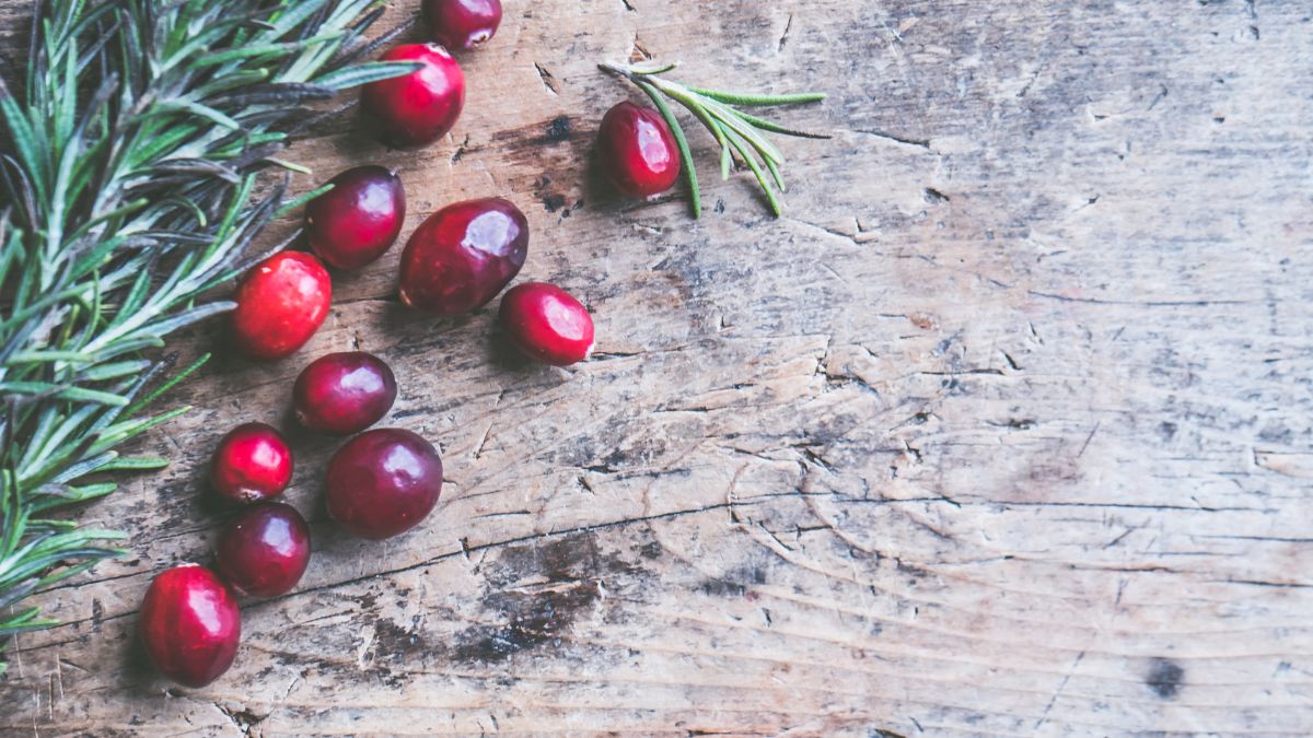 Frische Moosbeeren und Rosmarin auf einem rustikalen Holztisch.