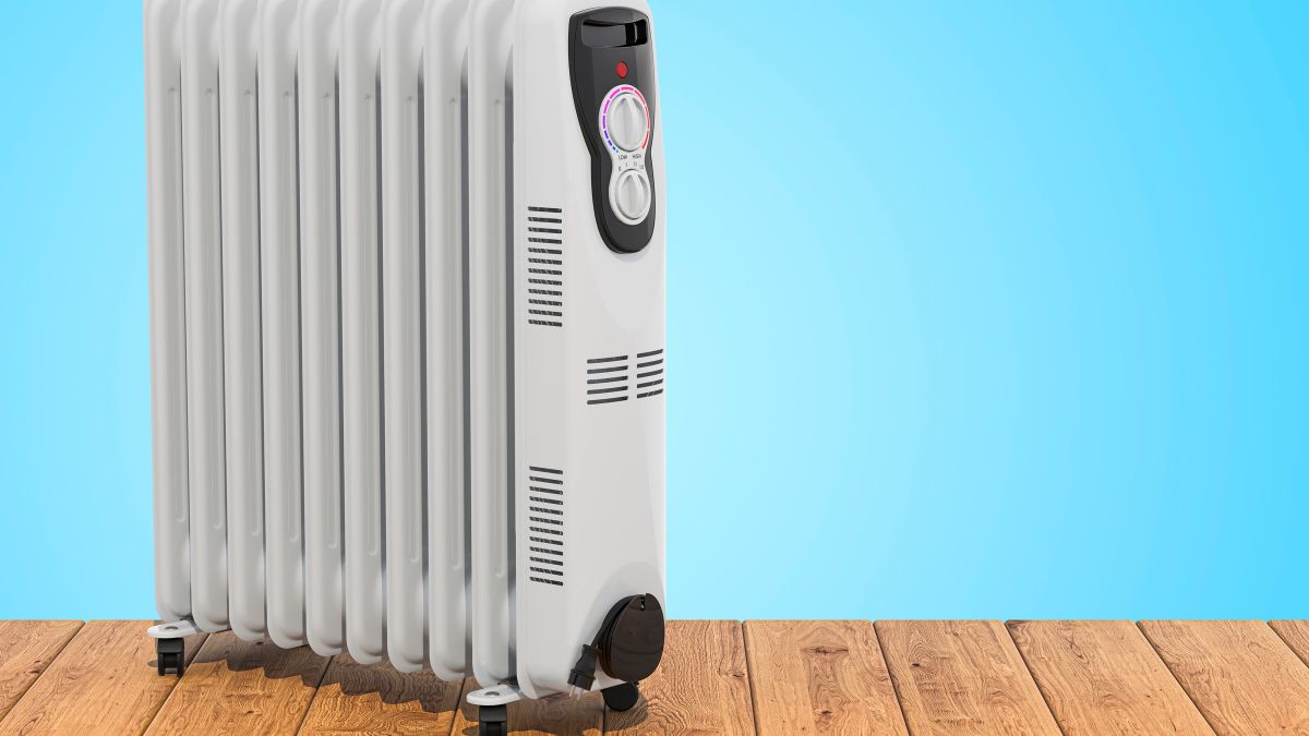 Ein moderner Ölradiator steht auf einem Holzboden vor einem blauen Hintergrund.