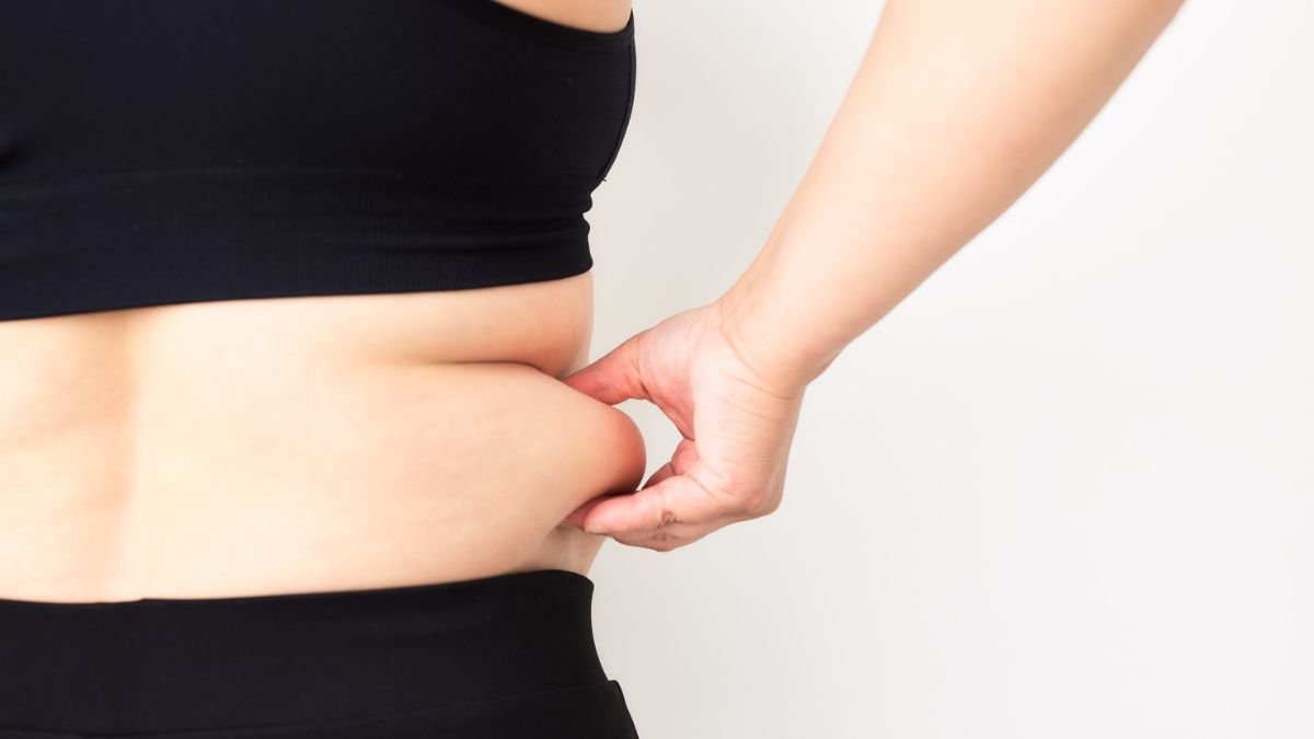 Eine Person greift an die seitlichen Bauchfalten, um Körperfett zu überprüfen.