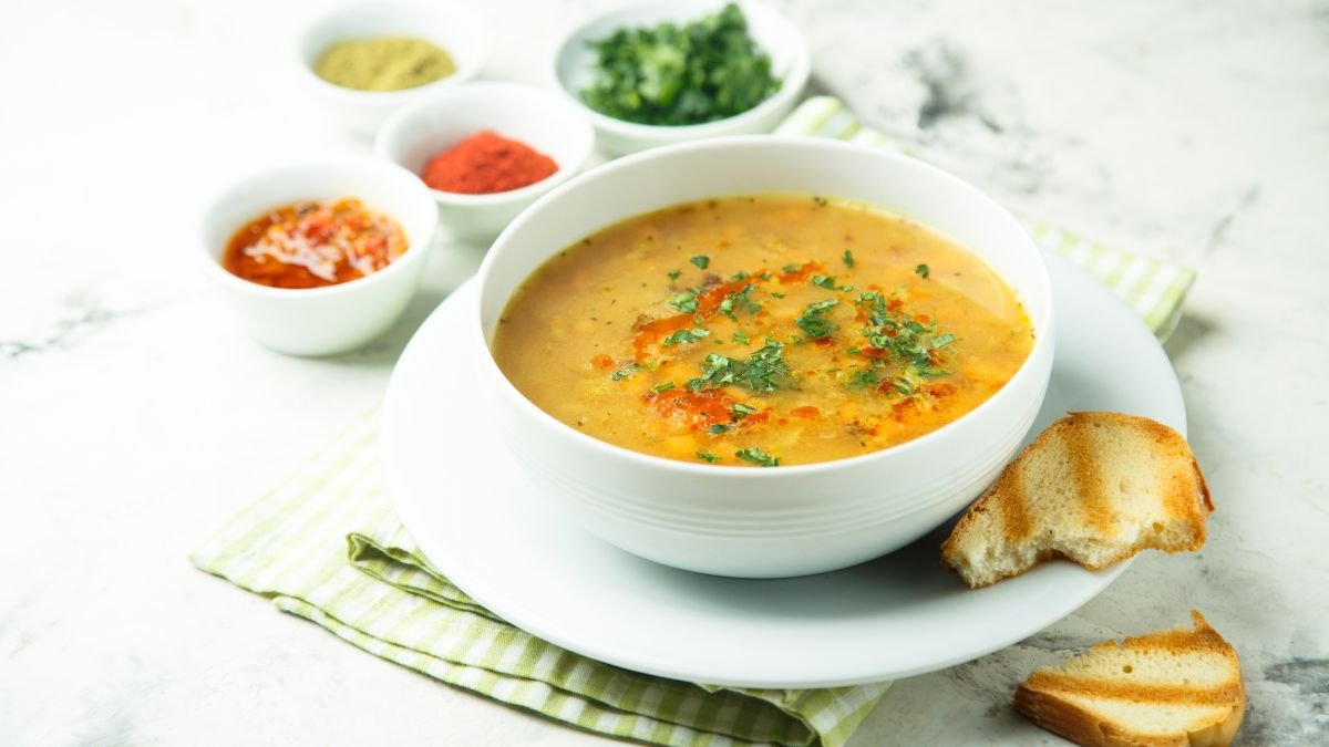 Eine Schüssel Taubensuppe mit frischen Kräutern und Gewürzen daneben.