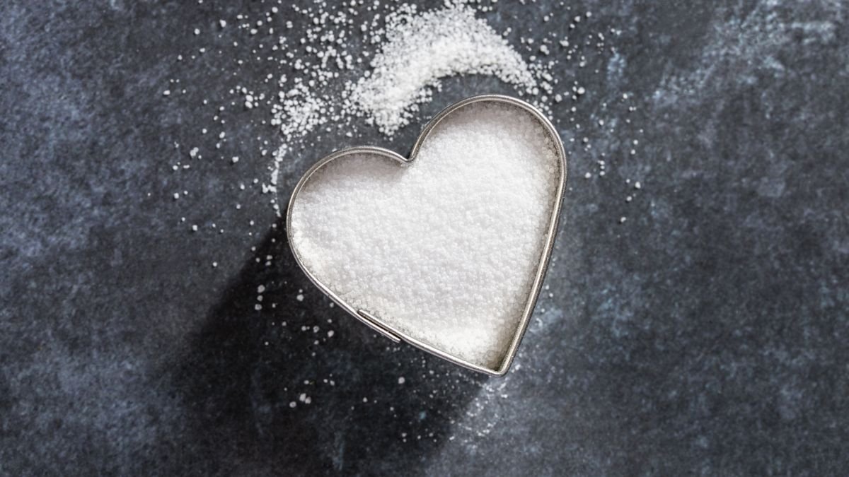 Eine herzförmige Ausstechform gefüllt mit weißem Pulver auf dunklem Hintergrund.