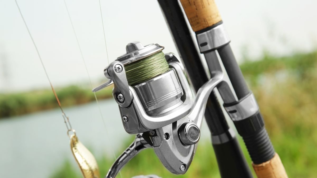 Nahaufnahme einer Angelrolle mit grüner Schnur und Angelrute im Hintergrund.