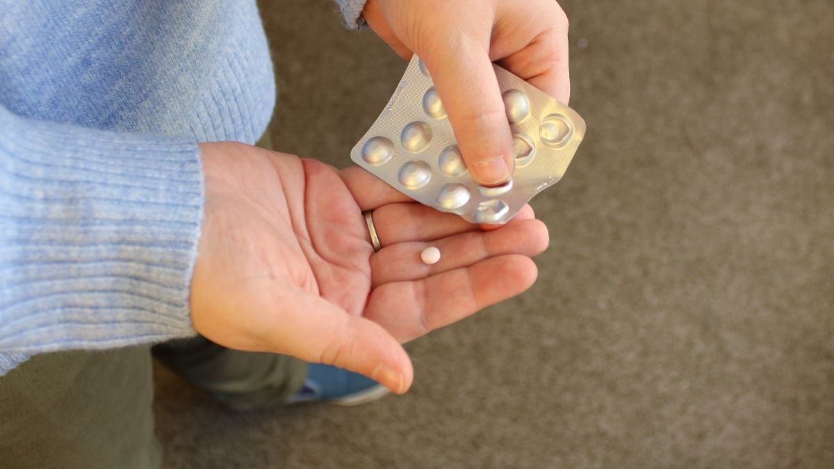 Eine Person hält eine Tablette aus einer Blisterpackung in der Hand.