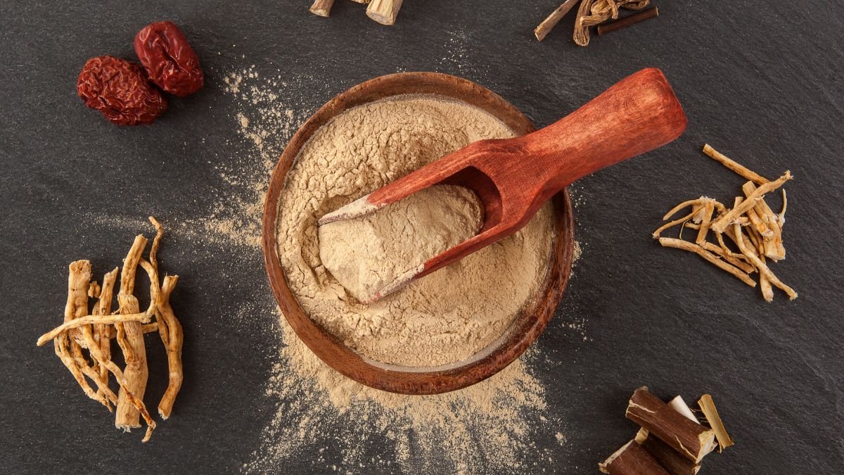 Eine Schale mit Ashwagandha-Pulver und Wurzeln auf einem dunklen Untergrund.