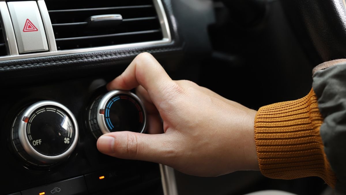 Eine Hand dreht den Temperaturregler der Autoklimaanlage auf kühl.