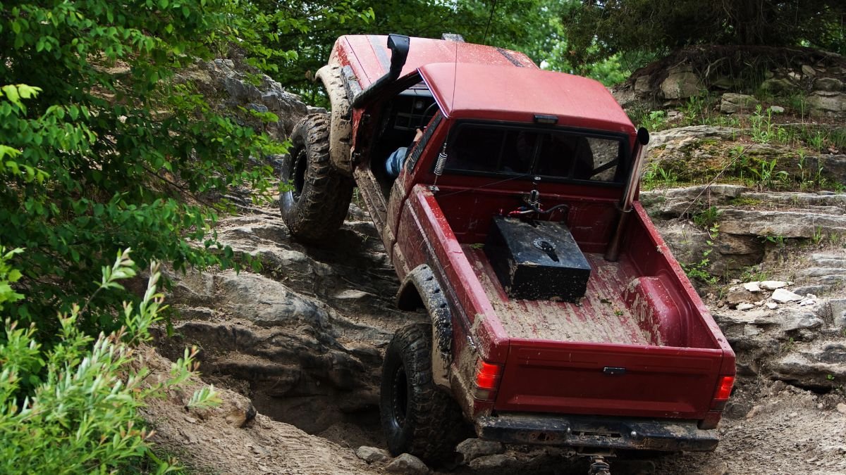 Ein roter Geländewagen fährt über einen steilen, felsigen Abhang.