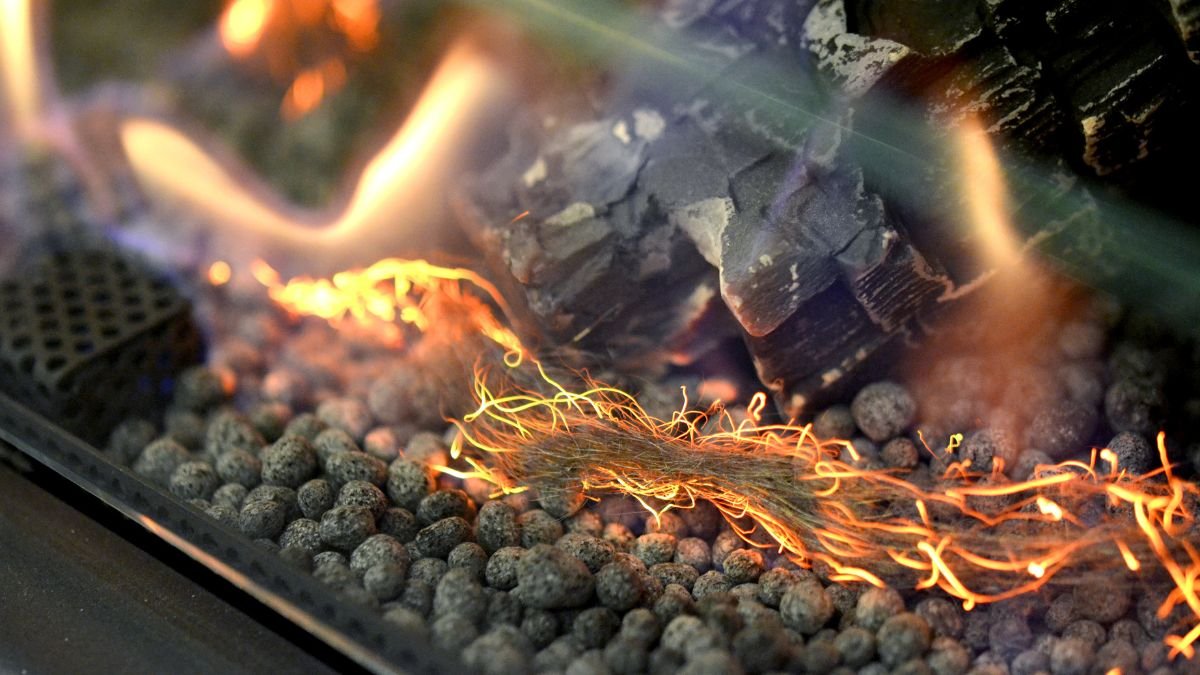 Nahaufnahme eines Biokamins mit flammenden Holzfasern und Steinen.