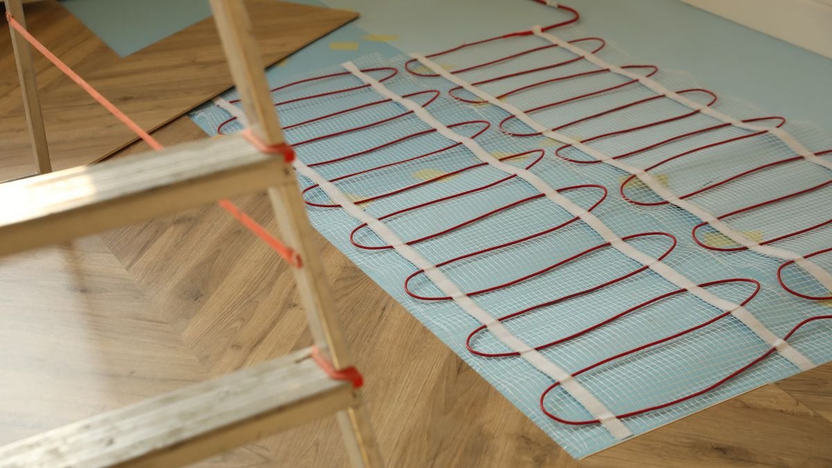 Ein Blick auf eine elektrische Fußbodenheizung mit roten Heizdrähten auf einem Untergrund.