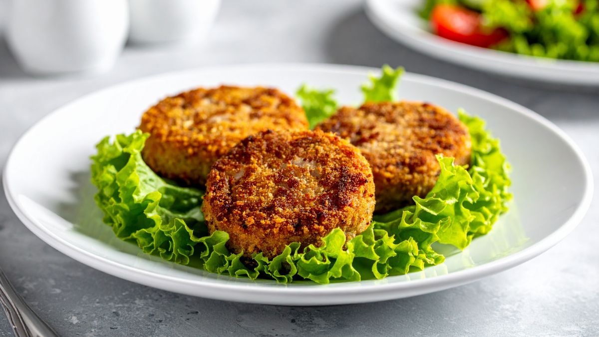 Drei knusprige pflanzliche Burger auf einem Bett aus frischem Salat.