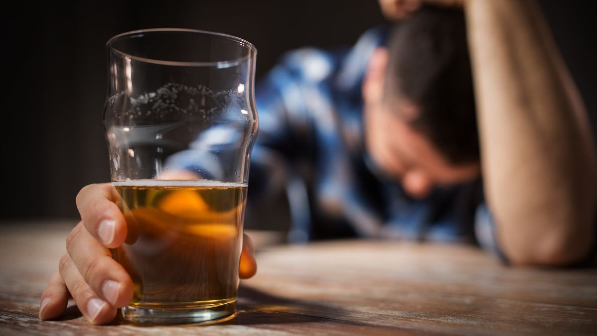 Ein Mann hält ein Glas Bier und zeigt Anzeichen von emotionaler Belastung.