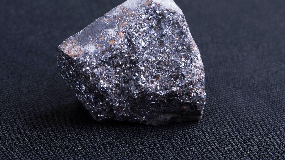 Ein Stück Galenit mit metallischem Glanz auf schwarzem Hintergrund.