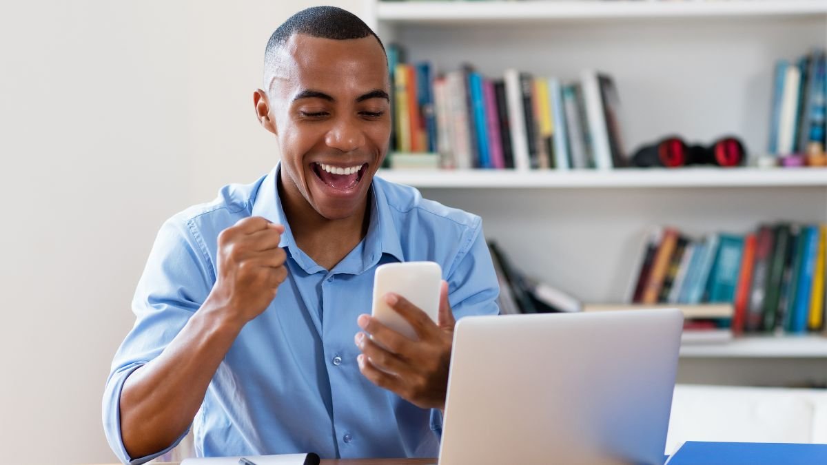 Ein junger Mann freut sich über eine Nachricht auf seinem Smartphone.