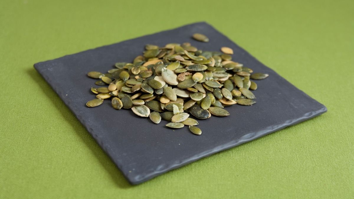 Eine Schale mit gerösteten Kürbiskernen auf einem schwarzen Teller.