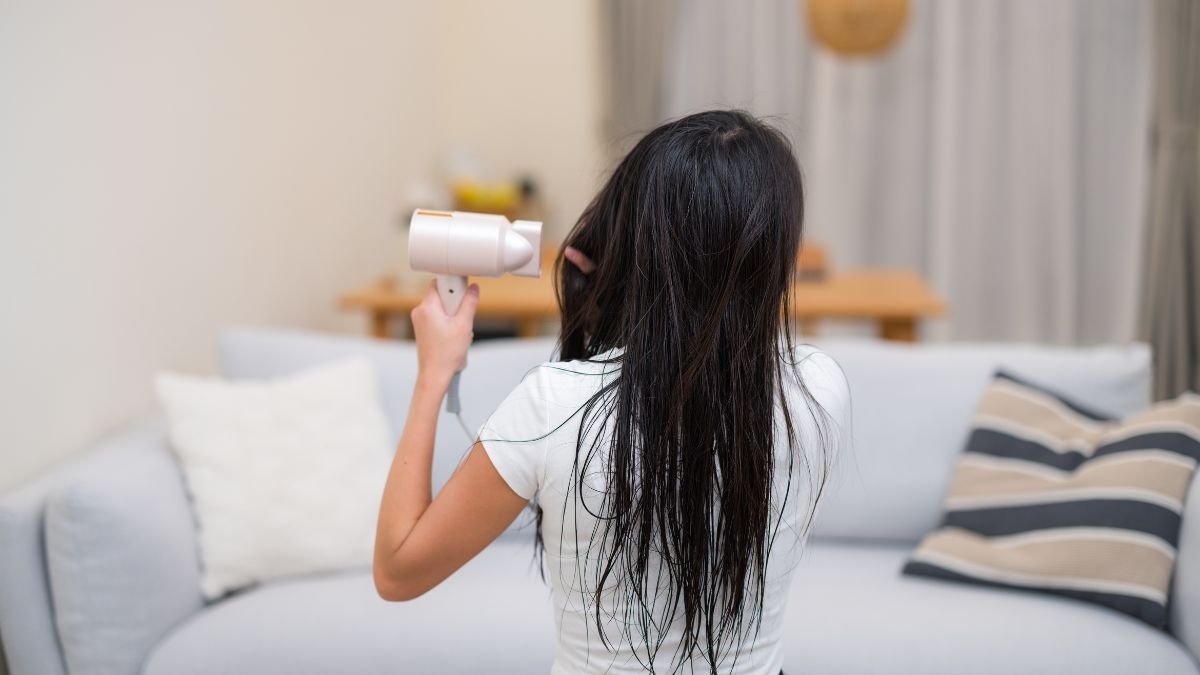 Eine Person mit nassen Haaren hält einen Ionen-Haartrockner in der Hand.