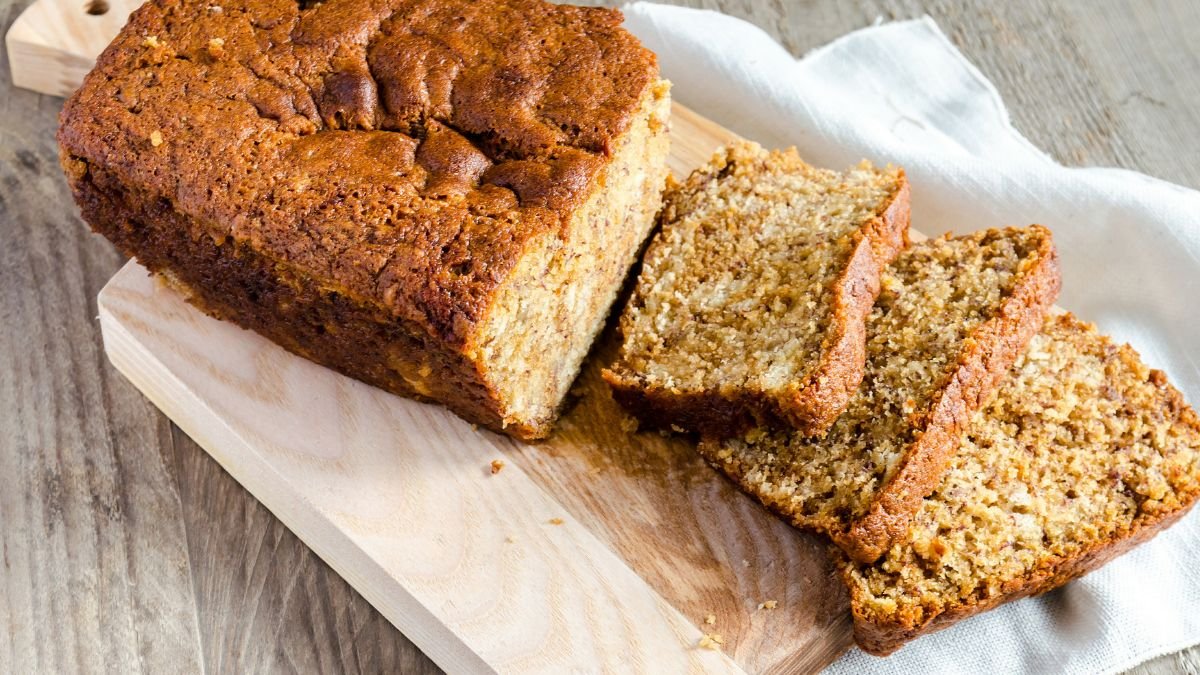 Ein frisch gebackenes Honigbrot auf einem Holzbrett, einige Scheiben sind geschnitten.