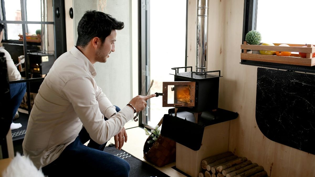 Ein Mann sitzt vor einem modernen Elektroheizofen und kontrolliert die Flamme.