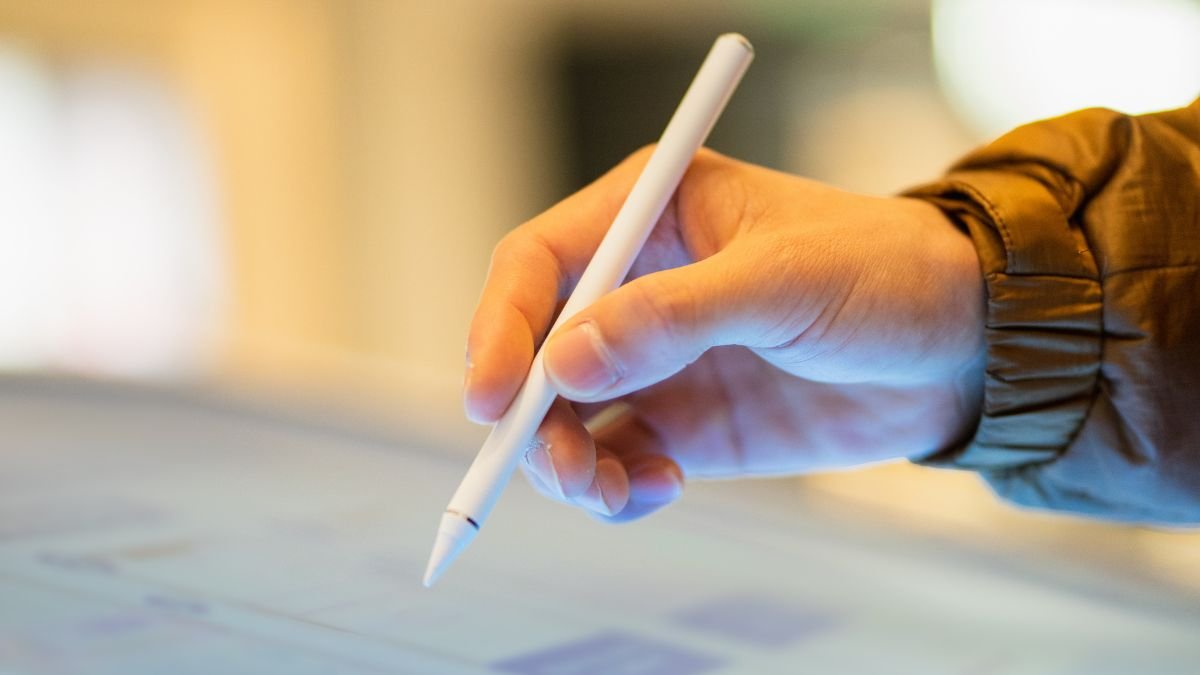 Eine Hand hält einen kapazitiven Stift über einem Touchscreen.