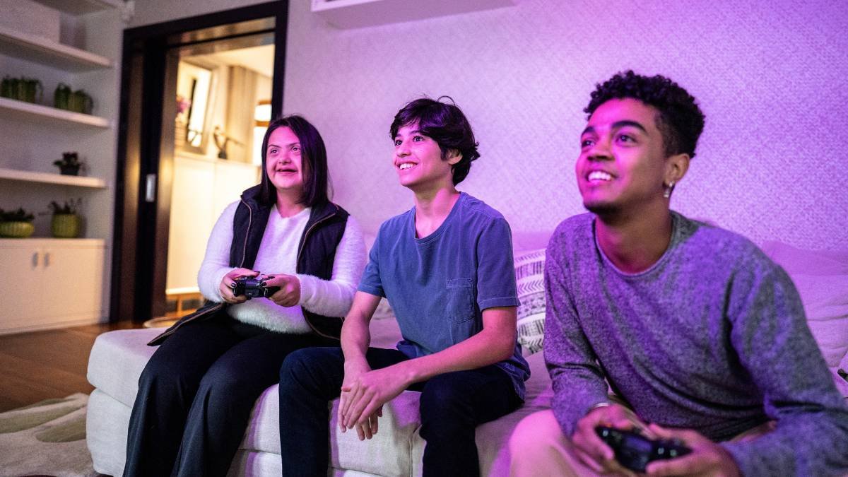 Drei Jugendliche spielen gemeinsam Videospiele in einem gemütlichen Raum.