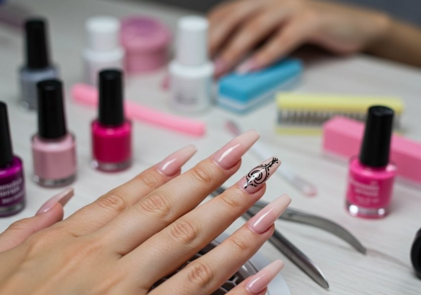 Eine Hand mit künstlichen Nägeln in Nude-Tönen und einem kunstvollen Design.