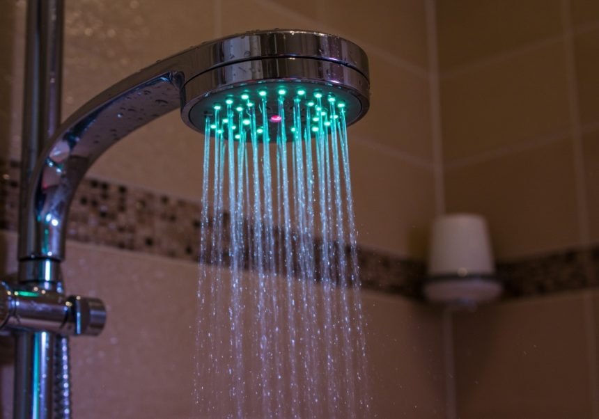 Ein LED-Duschkopf mit buntem Licht und Wasserstrahlen in einem modernen Badezimmer.