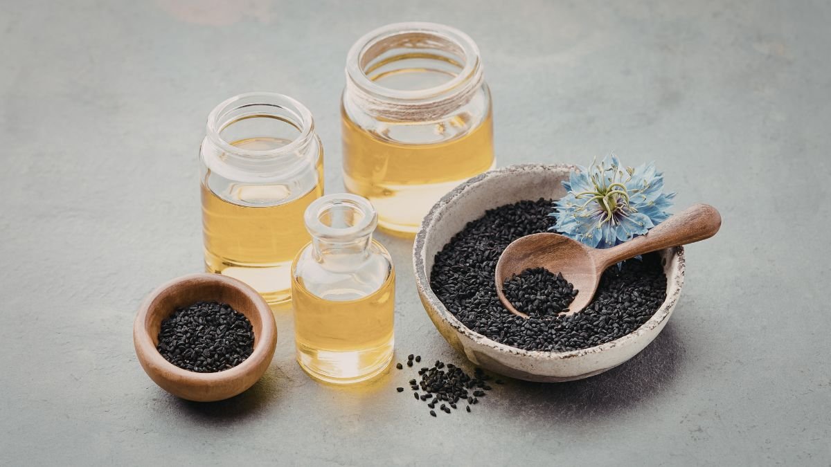 Drei Flaschen mit Mariendistelöl und eine Schale mit schwarzen Samen.