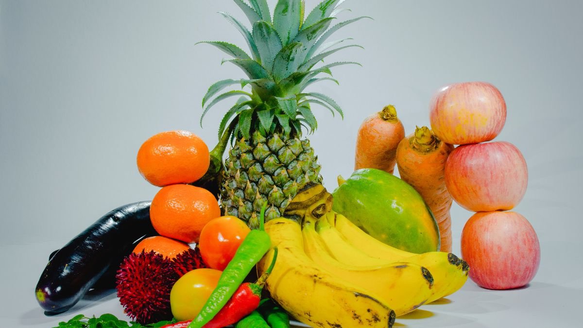 Bunte Auswahl an frischem Obst und Gemüse, darunter Ananas, Äpfel und Bananen.