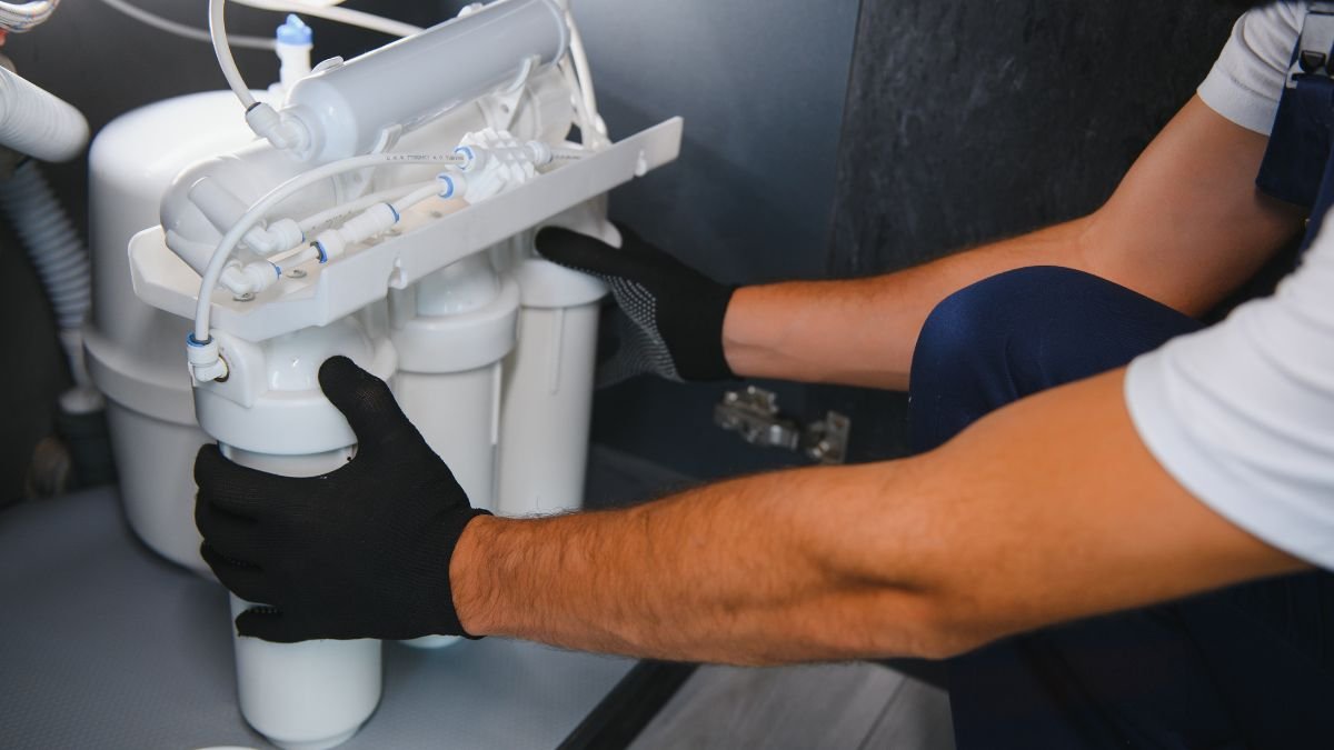 Eine Person installiert einen Osmose-Wasserfilter unter der Spüle.