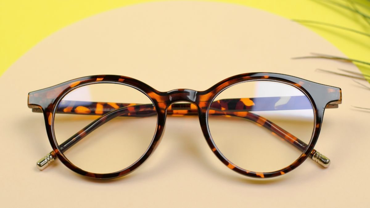 Eine modische Brille mit braunem Muster auf einem gelben Hintergrund.