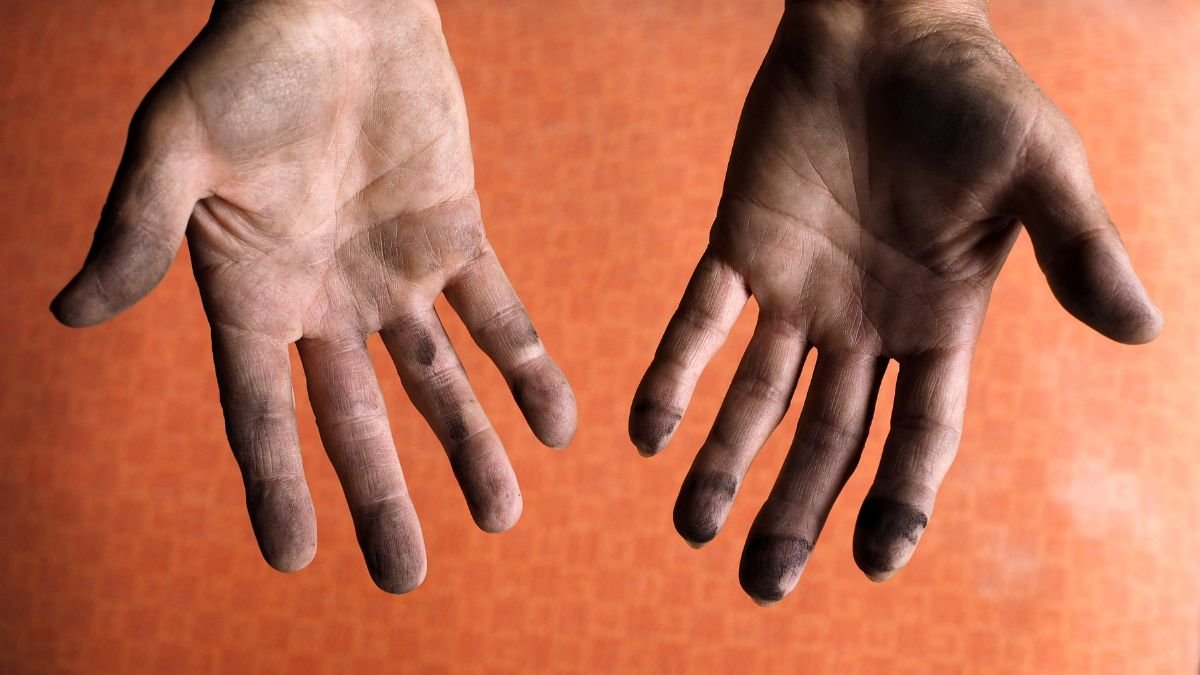 Zwei schmutzige Hände, die nach der Arbeit mit einer Handfettpresse aussehen.