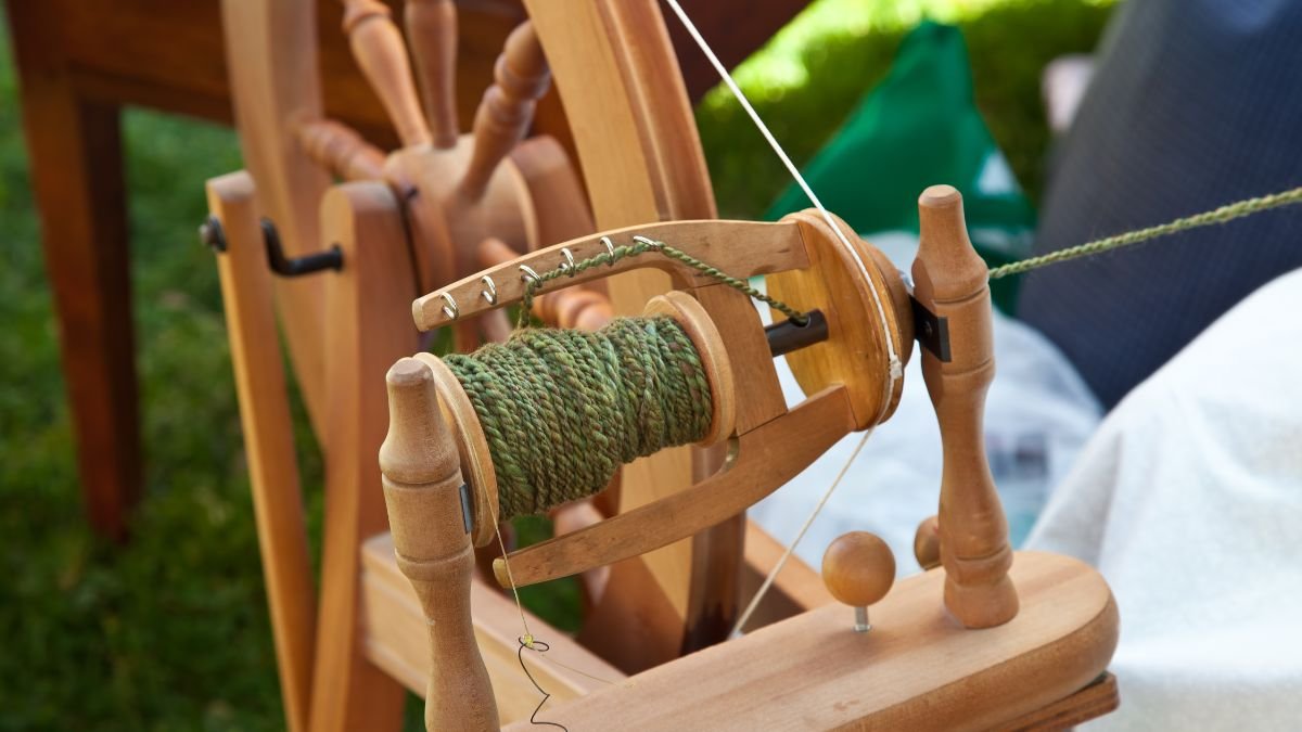 Ein Spinnrad mit grünem Garn auf der Spule, bereit zum Spinnen.
