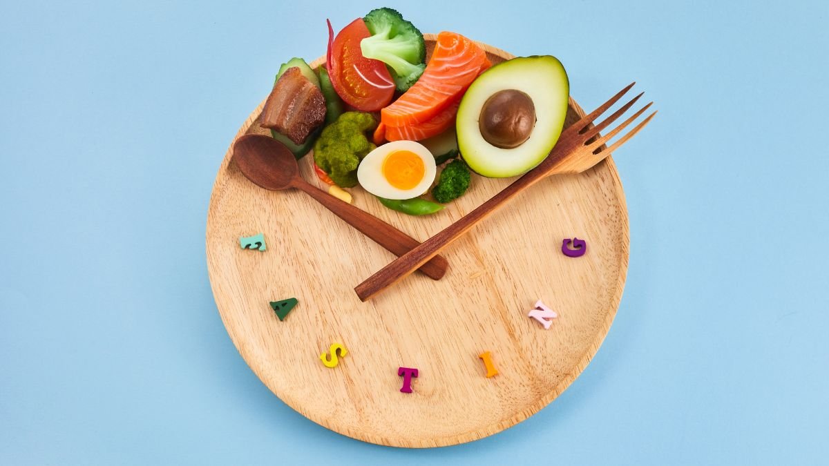 Ein Holzbrett mit gesunden Lebensmitteln wie Avocado, Lachs und Gemüse, um Fasten zu symbolisieren.