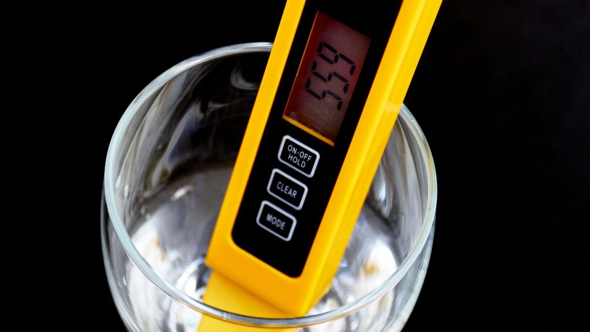 Ein TDS-Messgerät zeigt den Wert von Wasserqualität in einem Glas an.