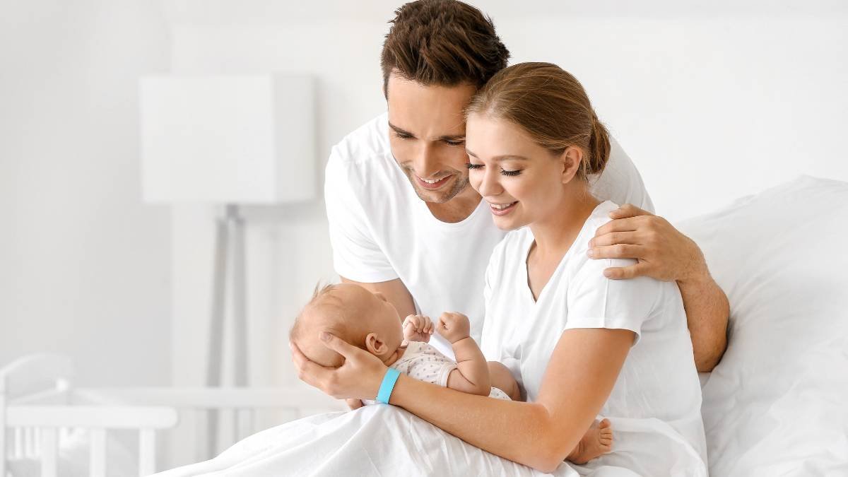 Ein Vater und eine Mutter halten ihr Neugeborenes in einem Krankenhauszimmer.