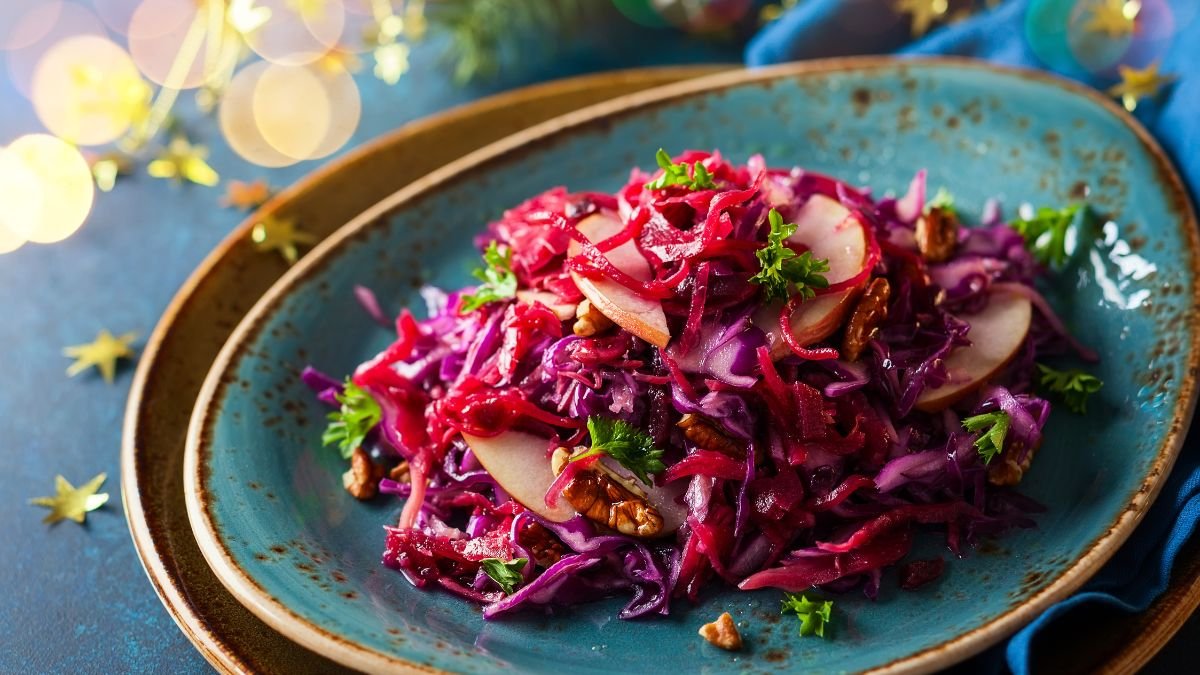 Ein bunter Salat aus Rotkohl, Äpfeln und Nüssen auf einem Teller.