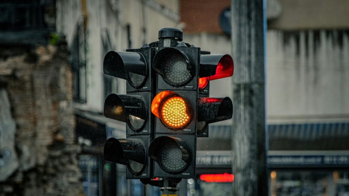 Eine Ampel zeigt rot und gelb, während es leicht regnet.