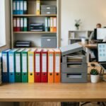 Ordentliche Büroablage mit beschrifteten Ordnern, Rechnungen und digitalen Dokumenten
