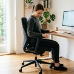 Person stellt Bürostuhl für eine ergonomische Sitzposition am Arbeitsplatz ein